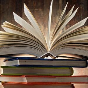 A book is open on top of some books.