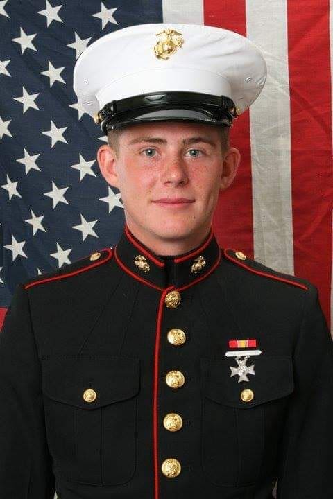 A man in uniform with an american flag behind him.