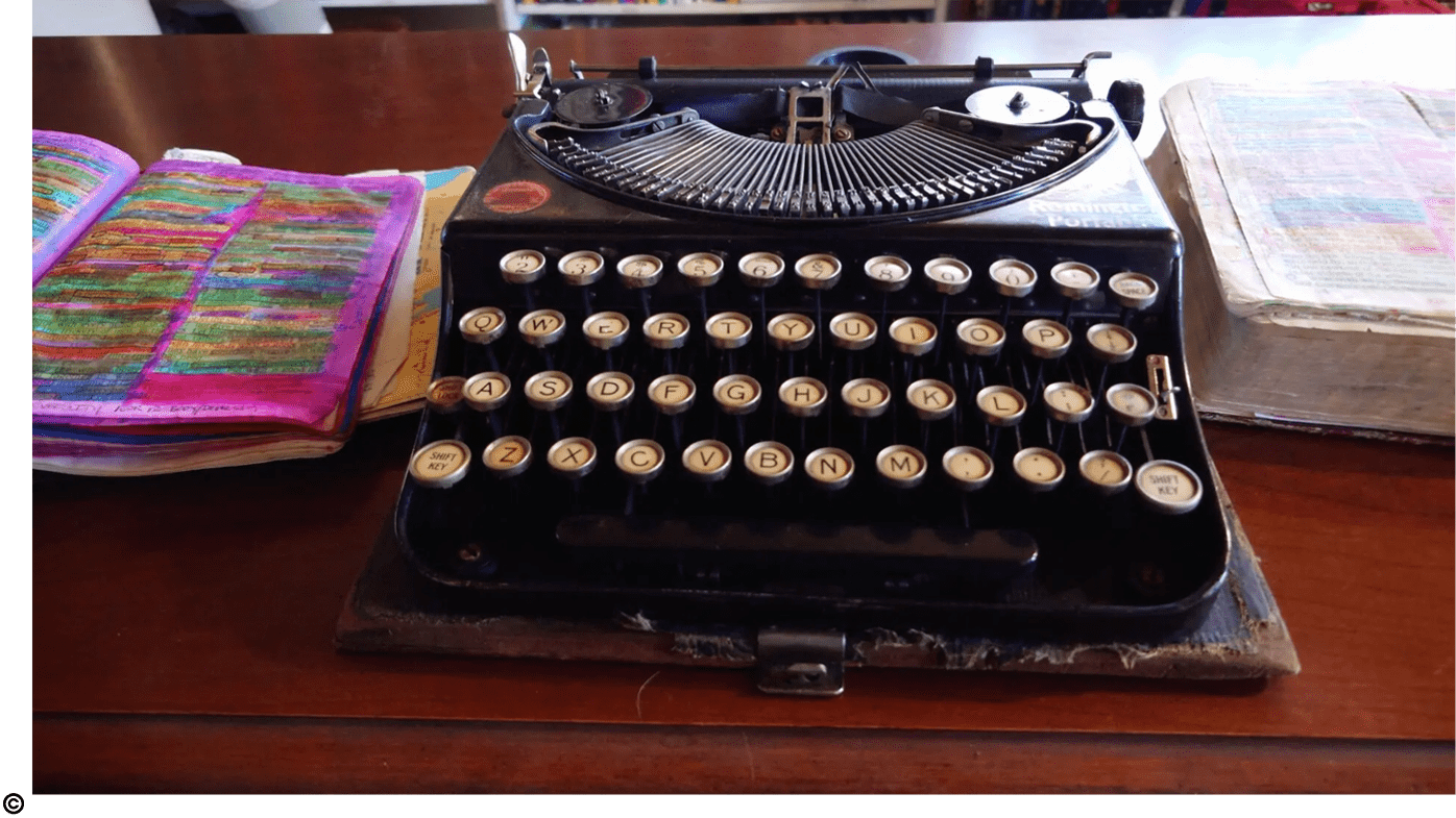 A typewriter sitting on top of a wooden table.