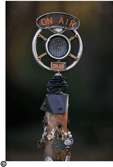 A sculpture of a clock on top of a wooden pole.