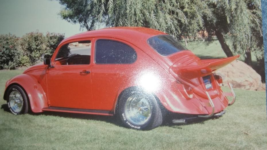 A red car is parked in the grass.