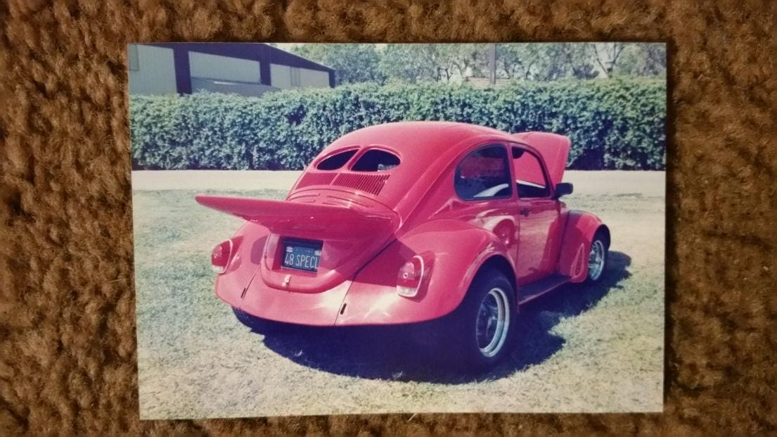 A red car parked in the grass with its trunk open.